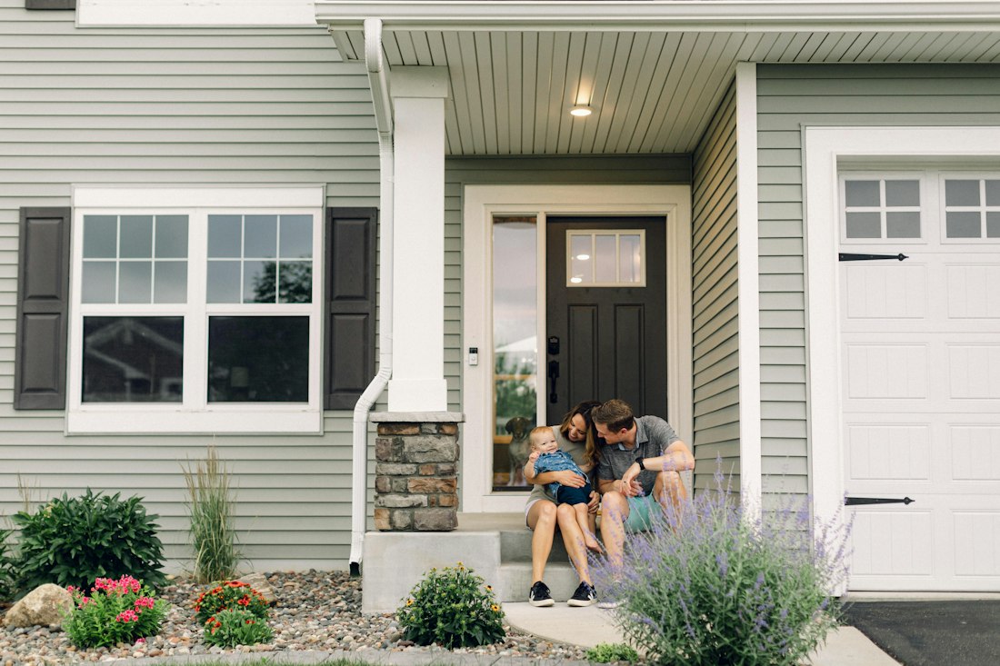 A family sitting on the front porch of their new home